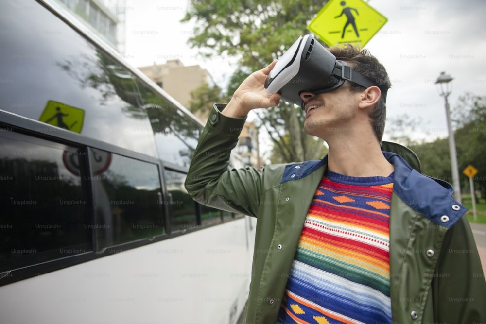 Un hombre de pie junto a un autobús con un casco de realidad virtual