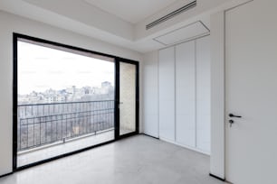 an empty room with a balcony and a view of the city