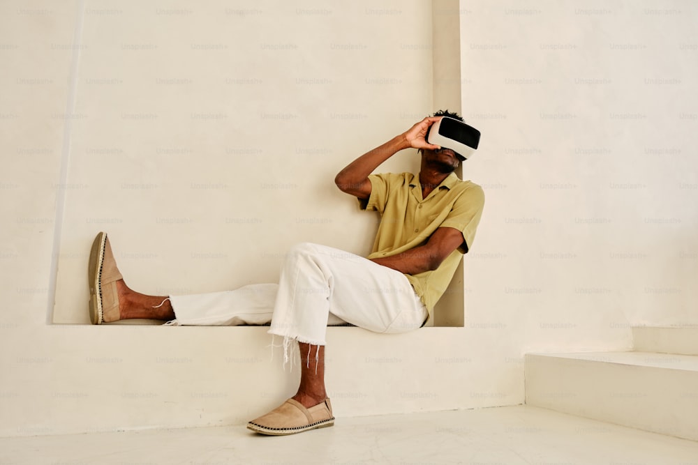 a man in a yellow shirt and white pants sitting on a ledge
