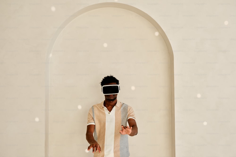 a man wearing a blindfold standing in front of a white wall