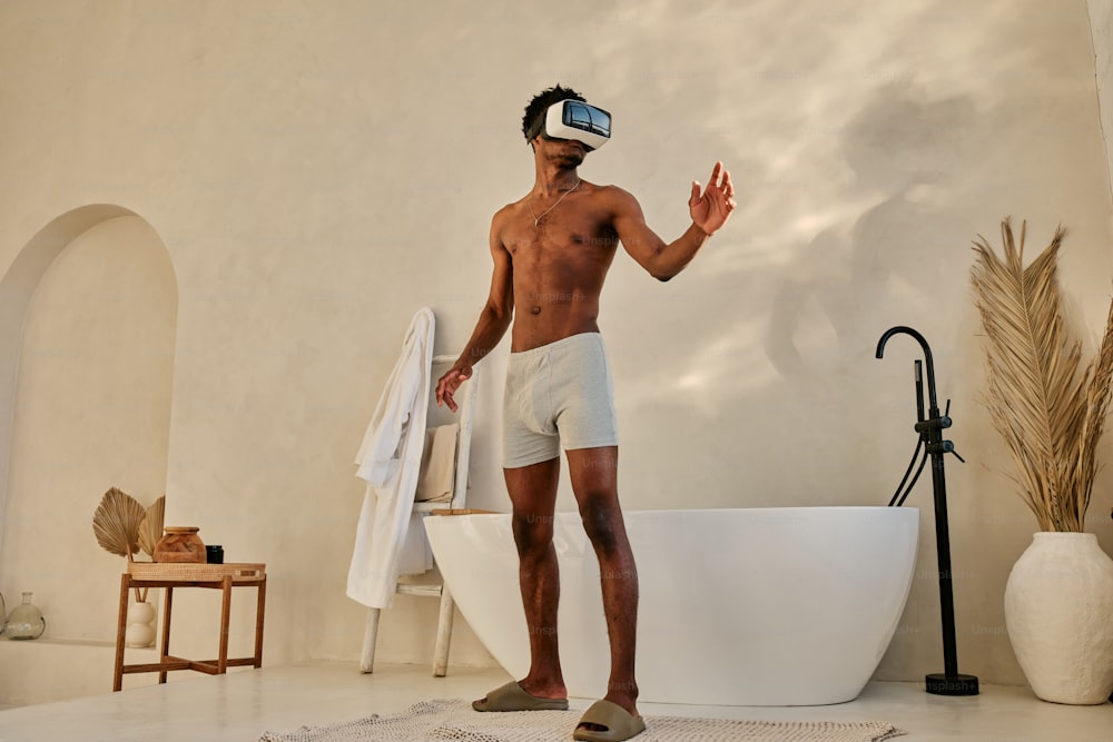 Un homme debout devant une baignoire portant un casque de réalité virtuelle