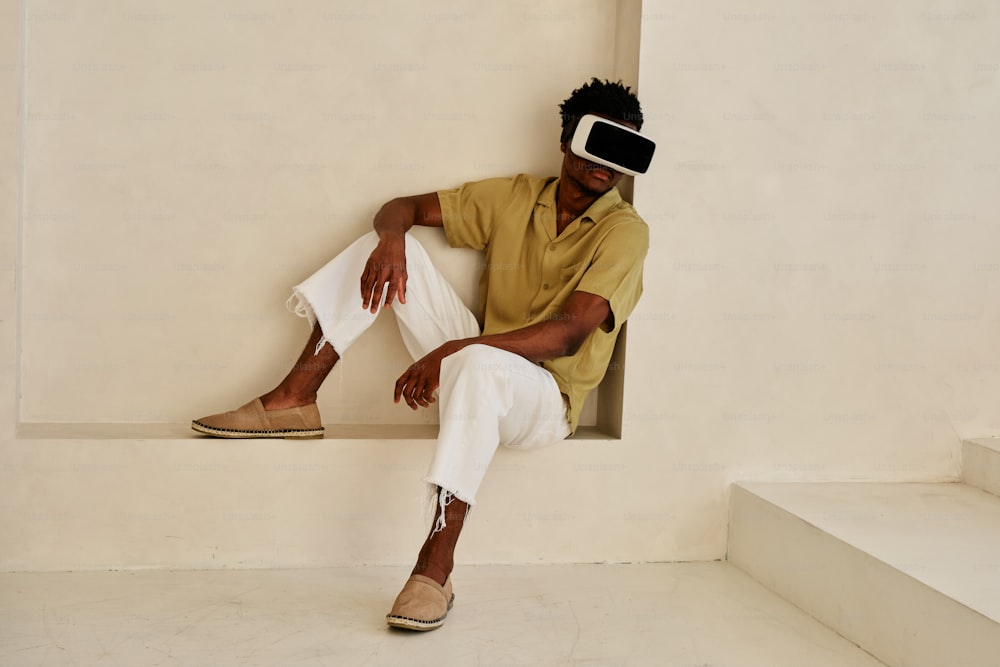 a man in a yellow shirt and white pants sitting on a ledge