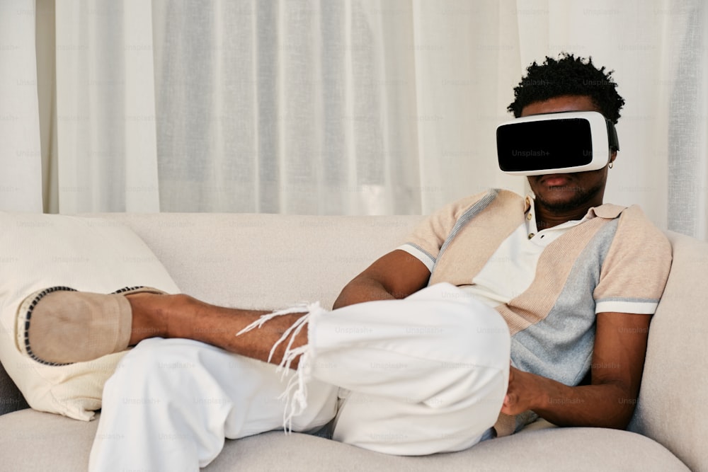 a man sitting on a couch wearing a virtual headset