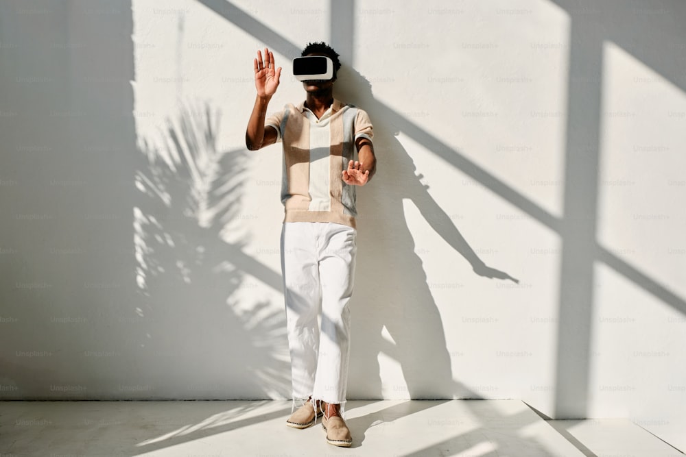 un uomo in piedi di fronte a un muro che indossa un visore per la realtà virtuale