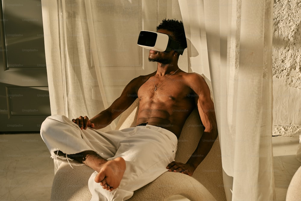 a shirtless man sitting on a chair with a blindfold