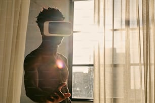 a man wearing a virtual reality headset standing in front of a window