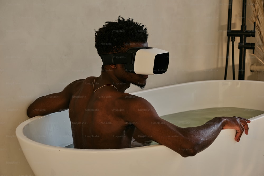 Un uomo in una vasca da bagno con un paio di occhiali virtuali in testa