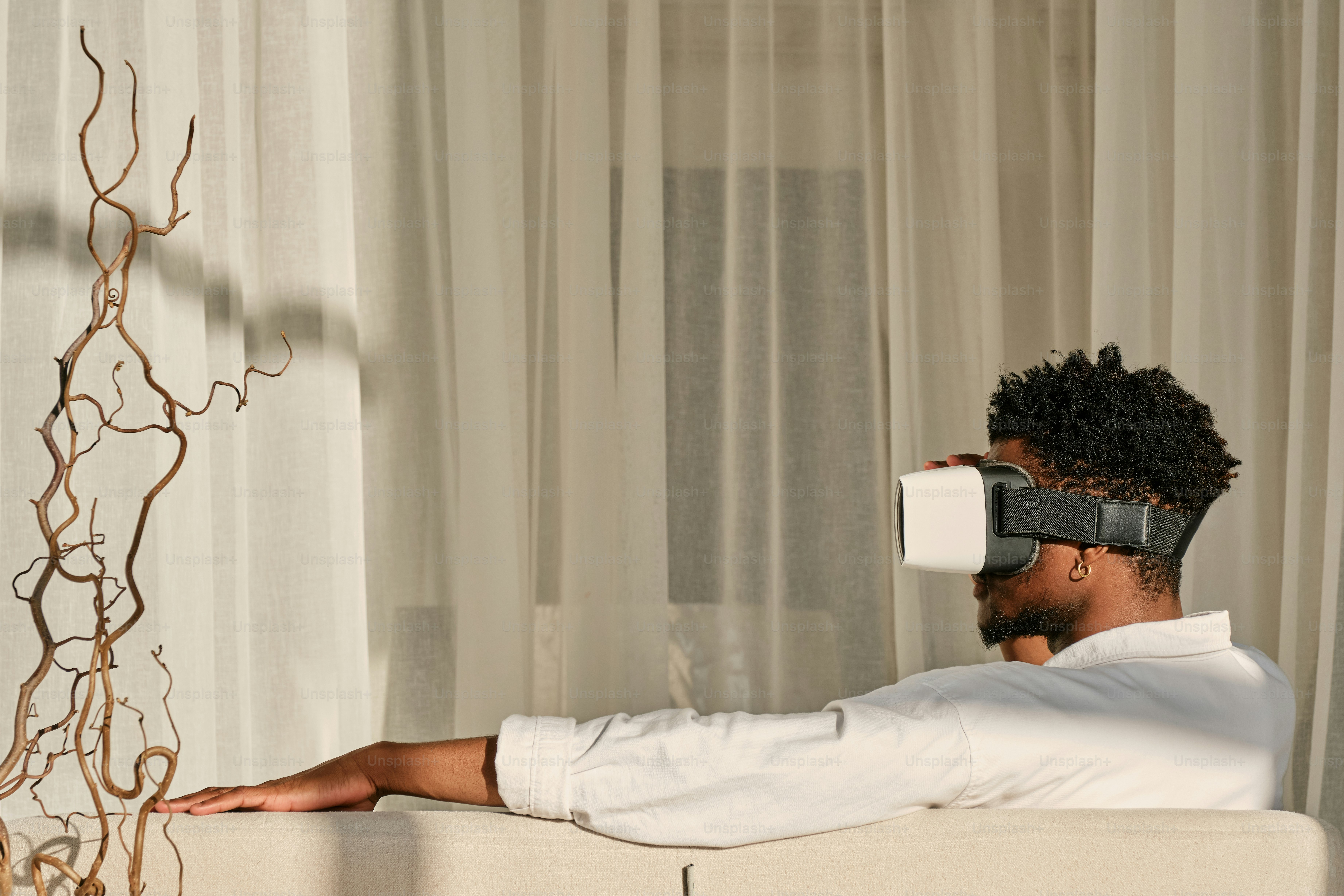 Ein Mann sitzt auf einer Couch und trägt eine virtuelle Brille