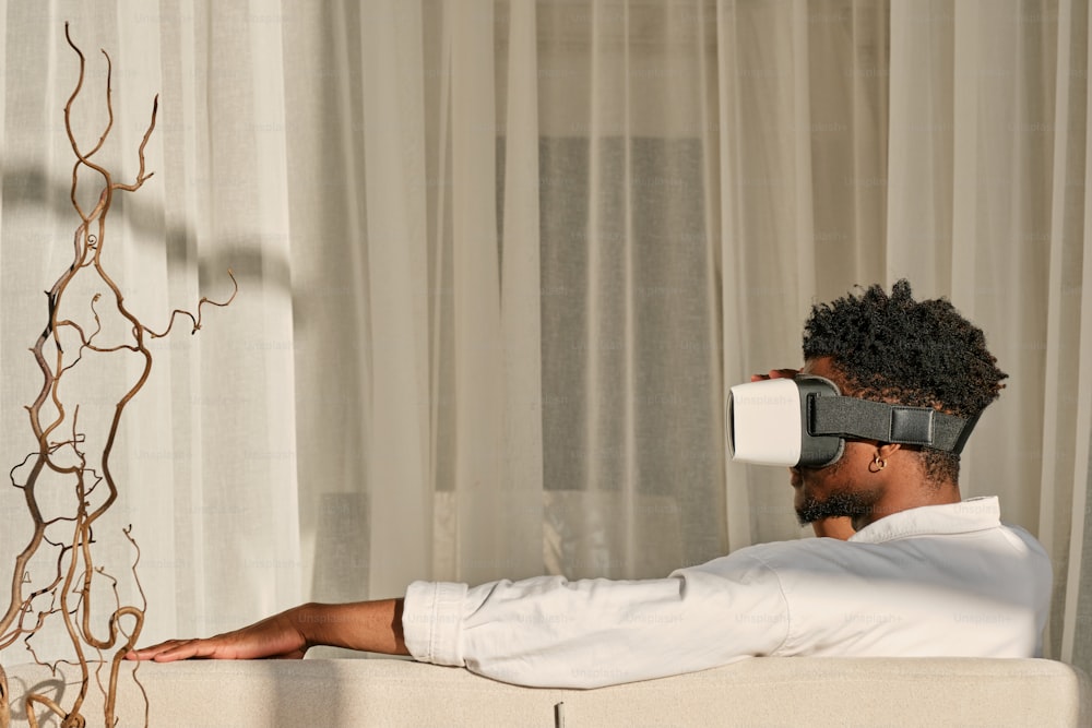a man sitting on a couch wearing a pair of virtual glasses