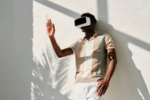 Un hombre con un casco de realidad virtual de pie contra una pared