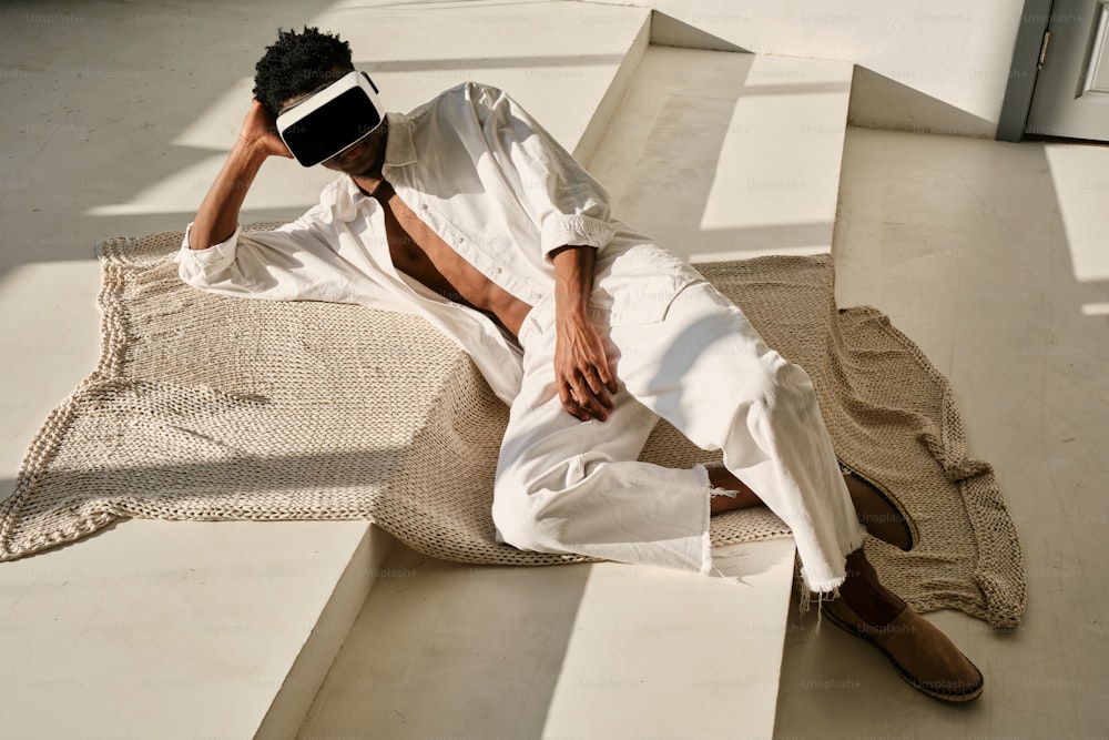 흰 셔츠와 흰 바지를 입고 바닥에 앉��아 있는 남자