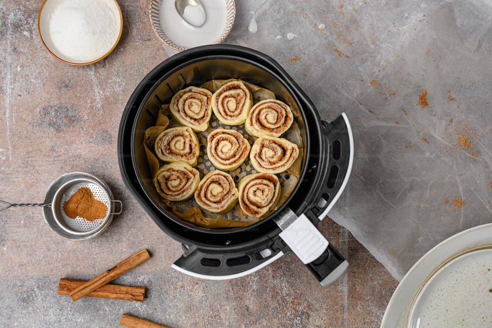 a pan filled with cinnamon rolls next to cinnamon sticks