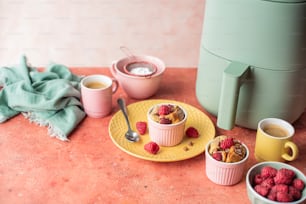 a yellow plate topped with raspberries next to two cups of coffee