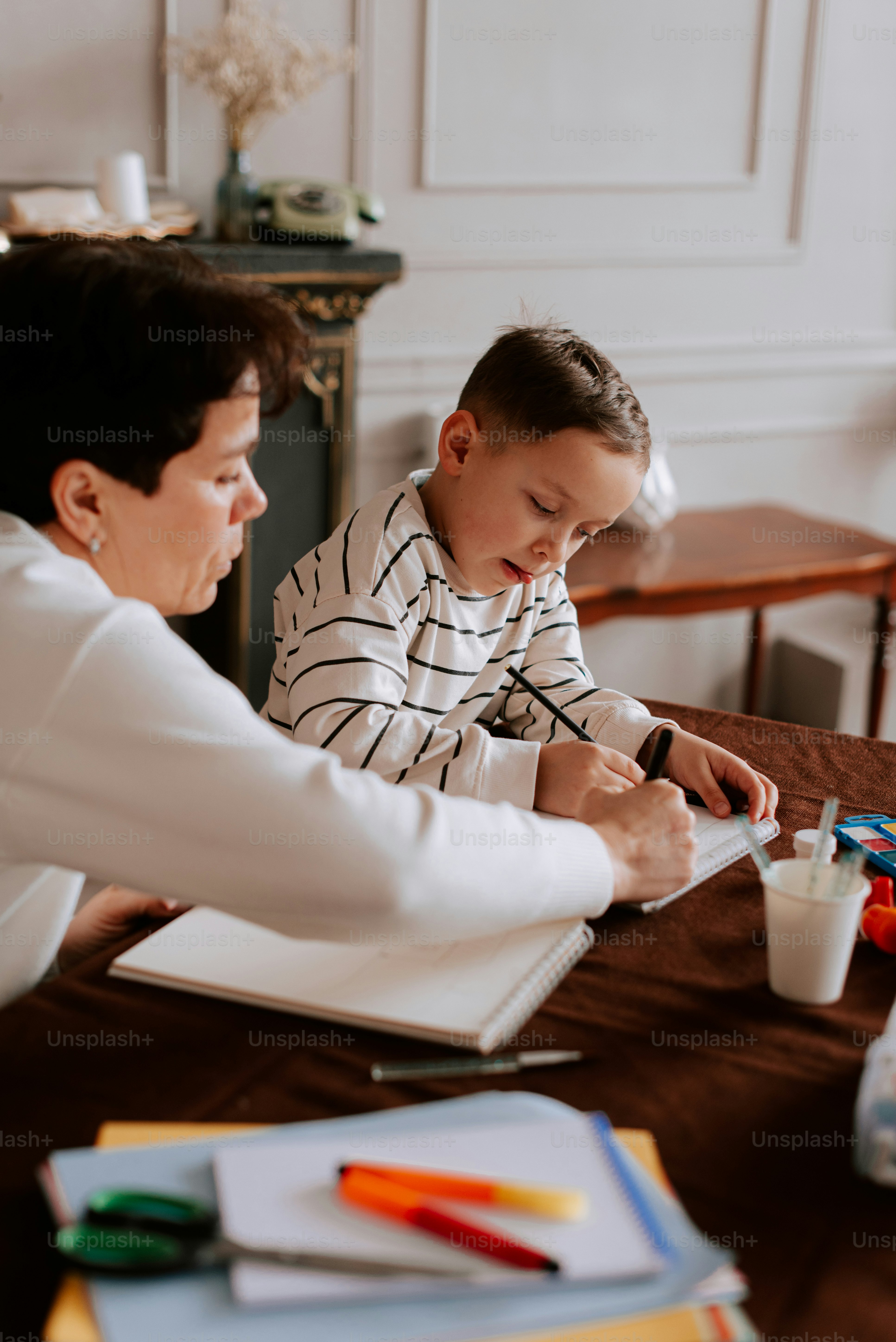 eine Frau, die mit einem kleinen Jungen an einem Tisch sitzt