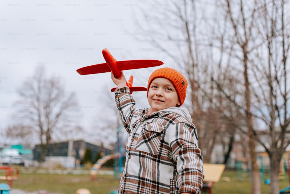 a young boy holding a red toy airplane