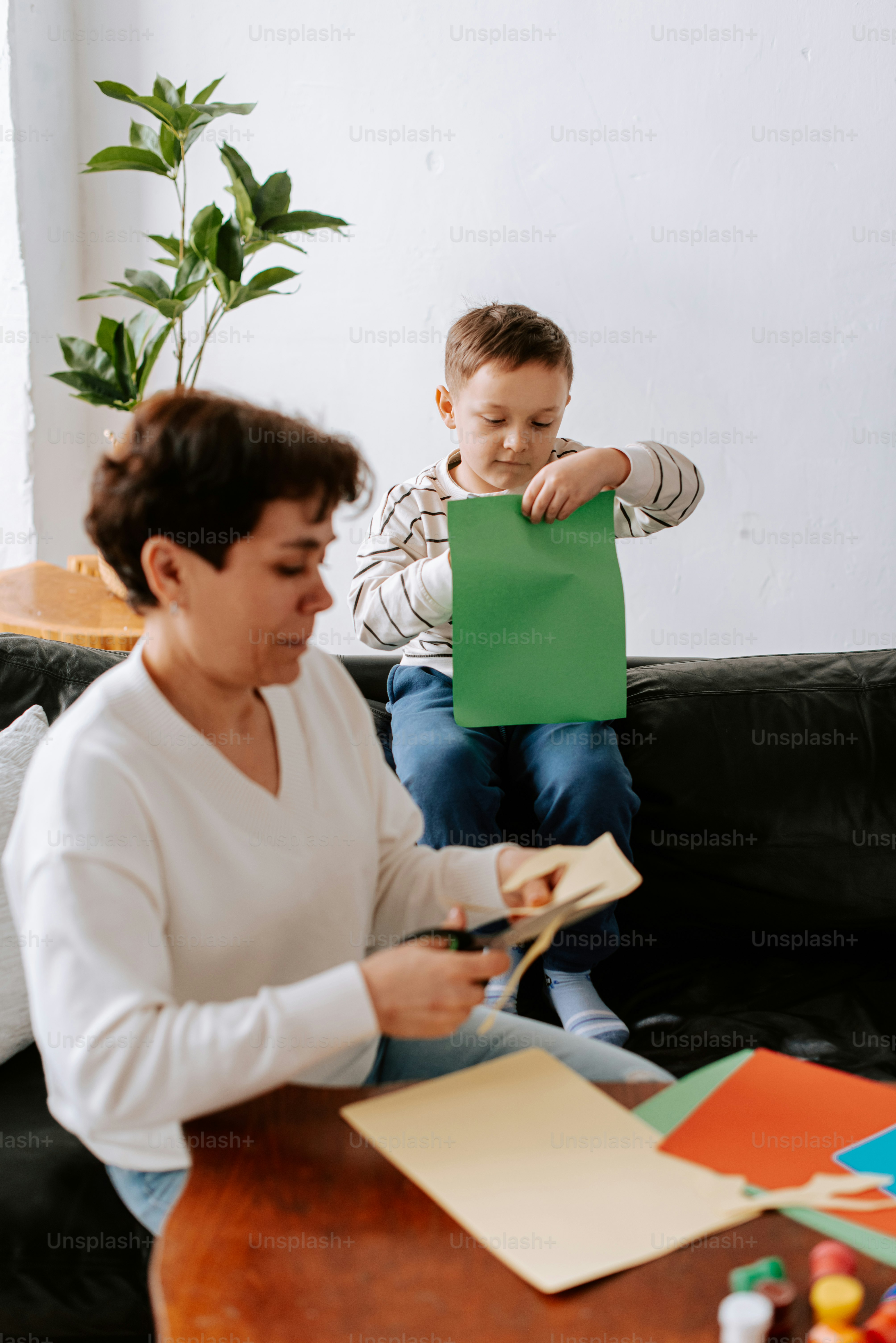 Eine Frau sitzt auf einer Couch neben einem kleinen Jungen