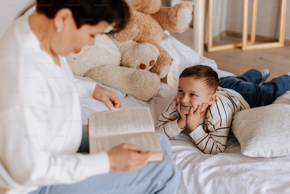 ベッドの上で子供に本を読み聞かせる女性