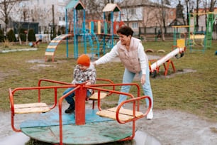 Una mujer empujando a un niño en un patio de recreo