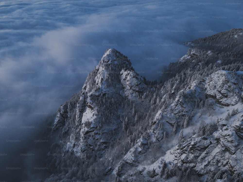 uma montanha coberta de neve cercada por nuvens