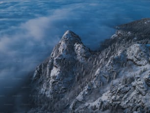 a mountain covered in snow surrounded by clouds