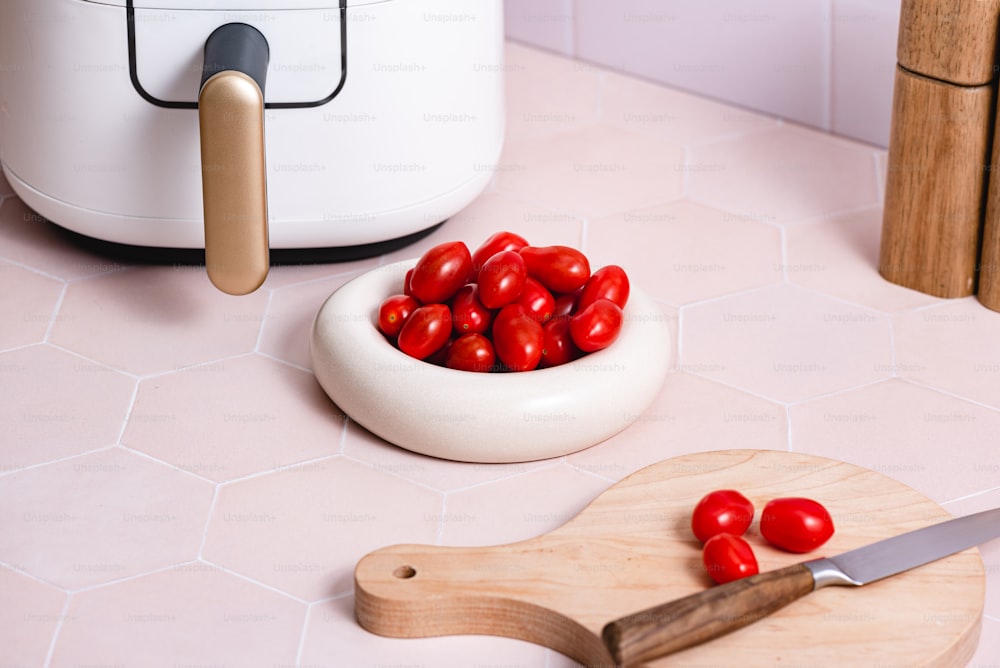 a bowl of tomatoes next to a cutting board