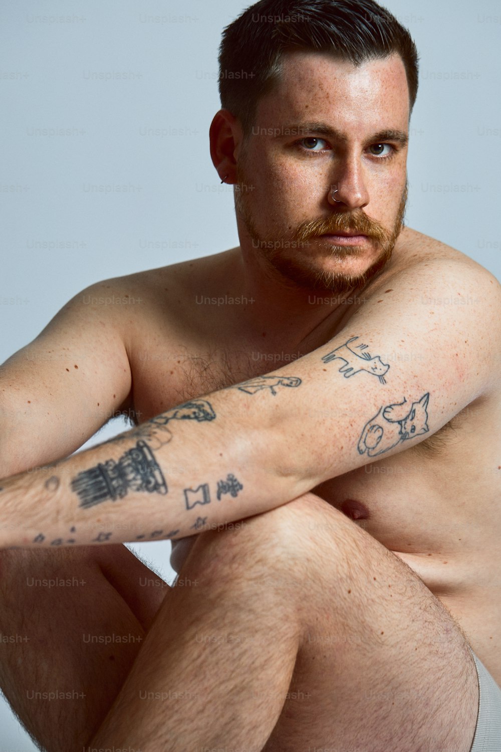 Un hombre sin camisa con un tatuaje en el brazo