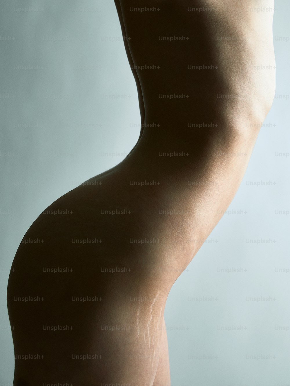 El cuerpo desnudo de una mujer se muestra sobre un fondo gris