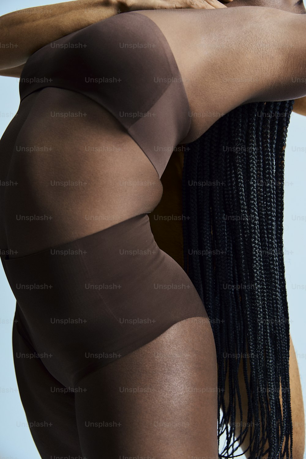 una mujer con un body marrón con largas trenzas