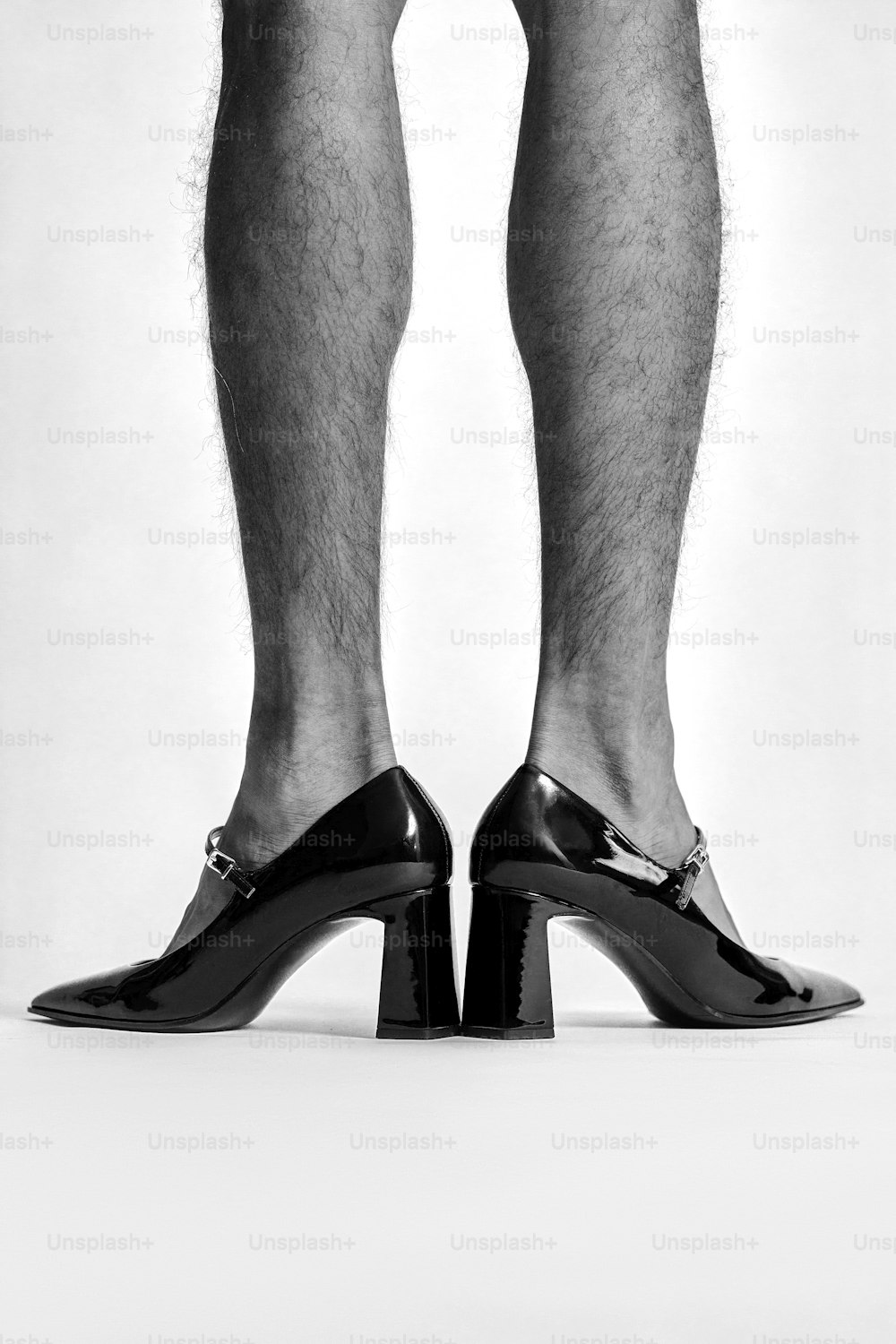 하이힐을 신은 남자의 다리를 찍은 흑백 사진