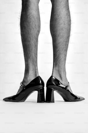 a black and white photo of a man's legs wearing high heels