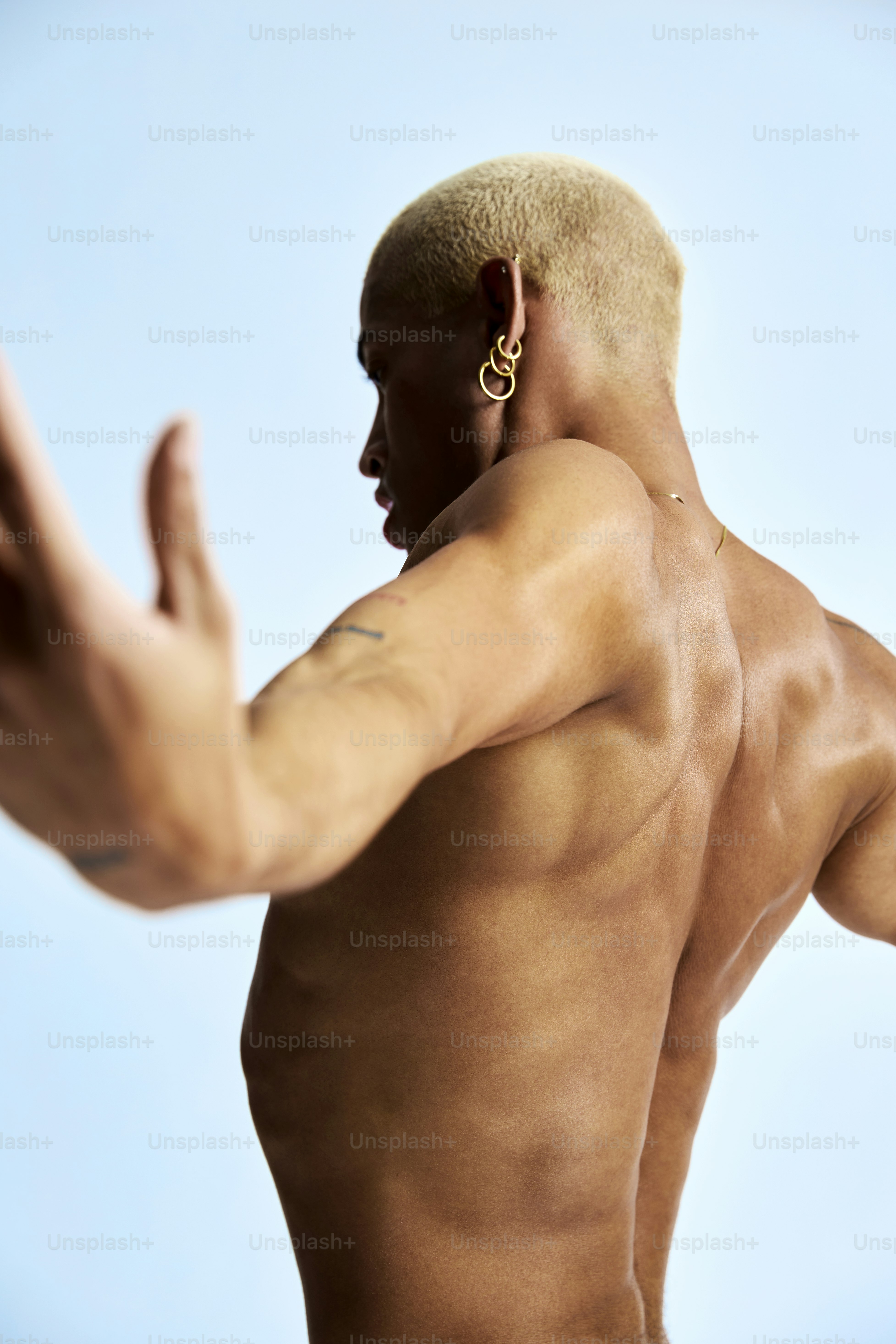 Ein Mann ohne Hemd streckt seinen Arm aus