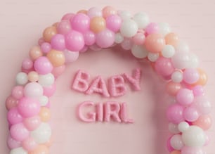 a baby girl balloon arch with the word baby girl spelled out