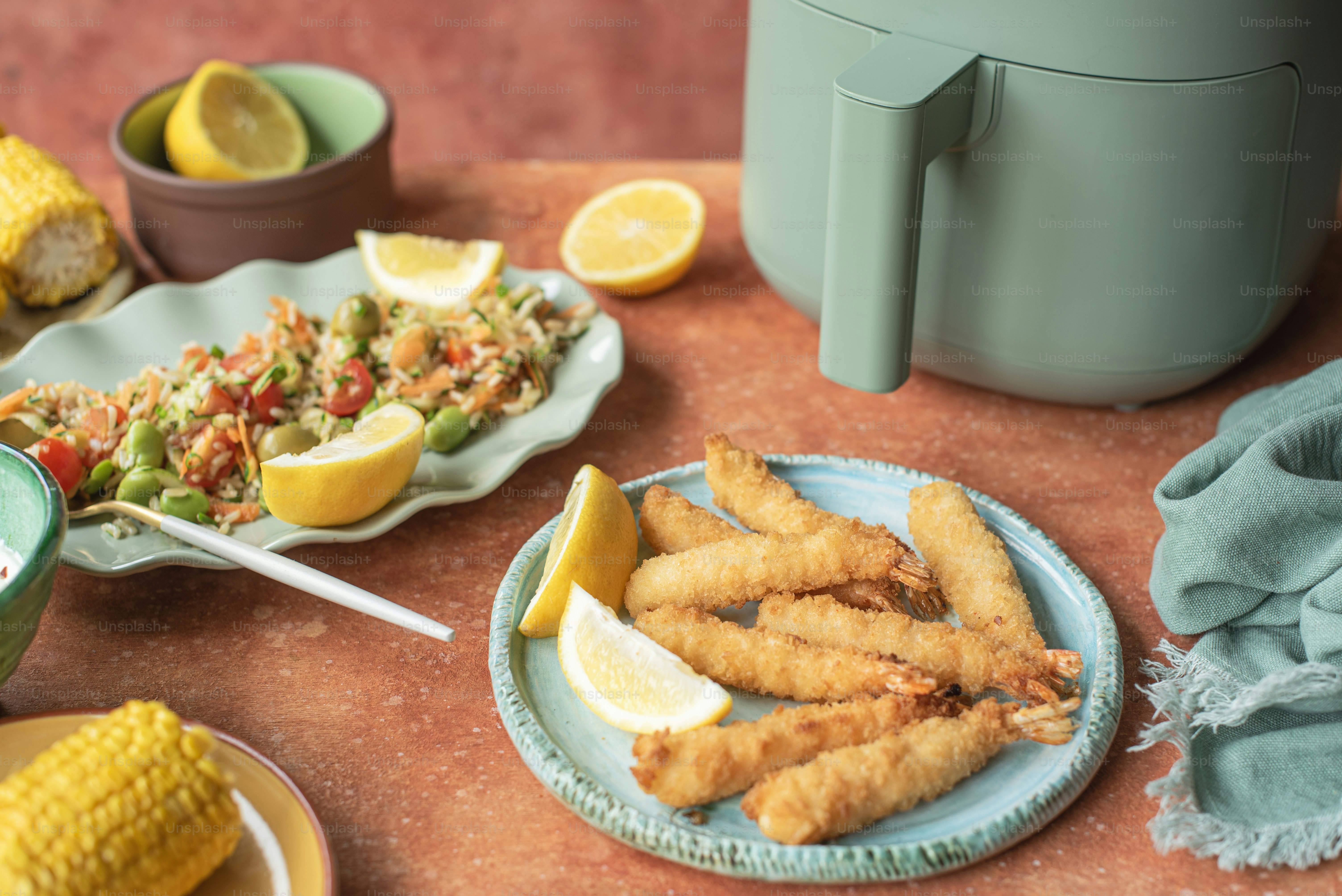 a table topped with plates of food and corn on the cob