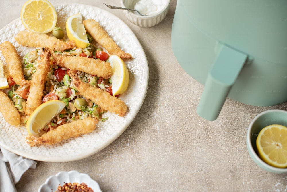 a white plate topped with fried fish next to a container of sauce