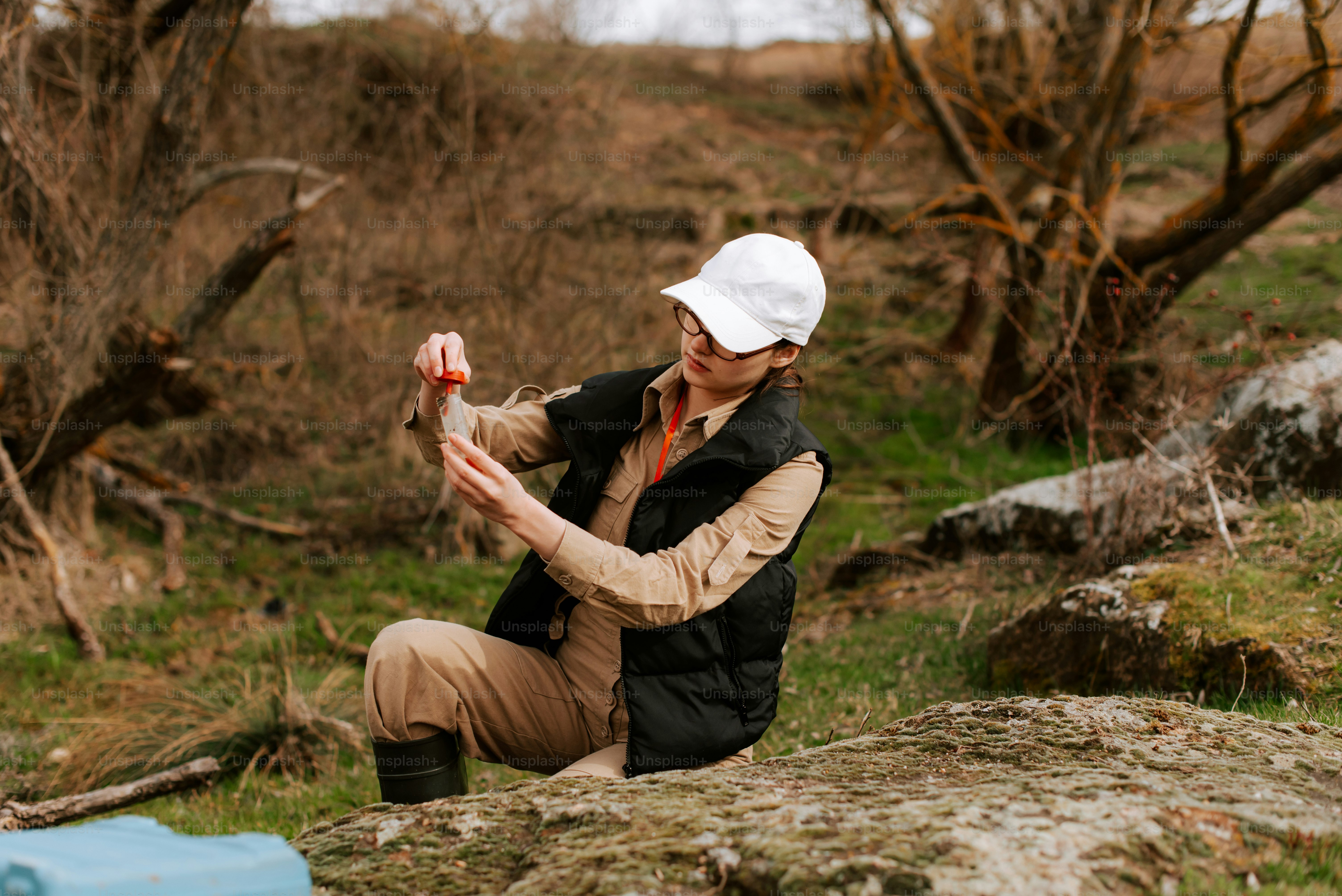 들판의 바위 위에 앉아 있는 여자