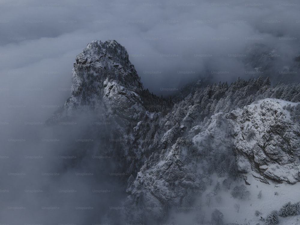 a mountain covered in snow surrounded by clouds