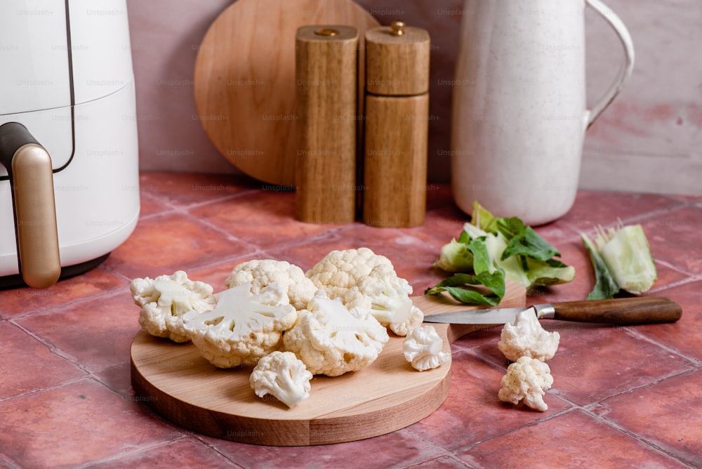 a cutting board with cauliflower on it next to a knife