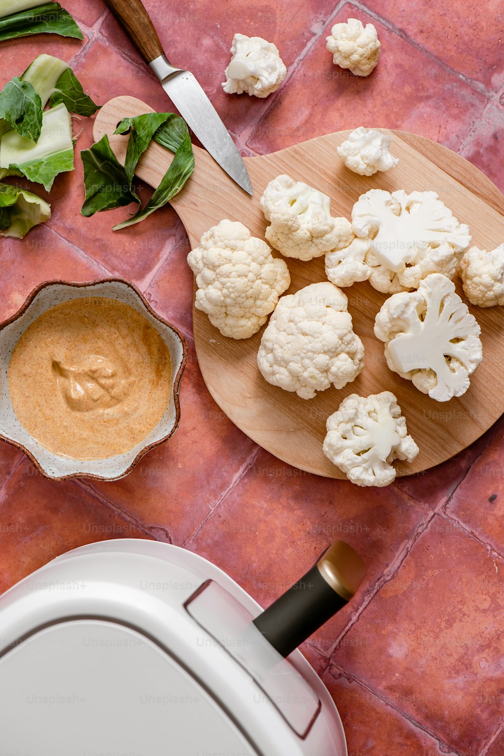 a cutting board with cauliflower and a bowl of sauce