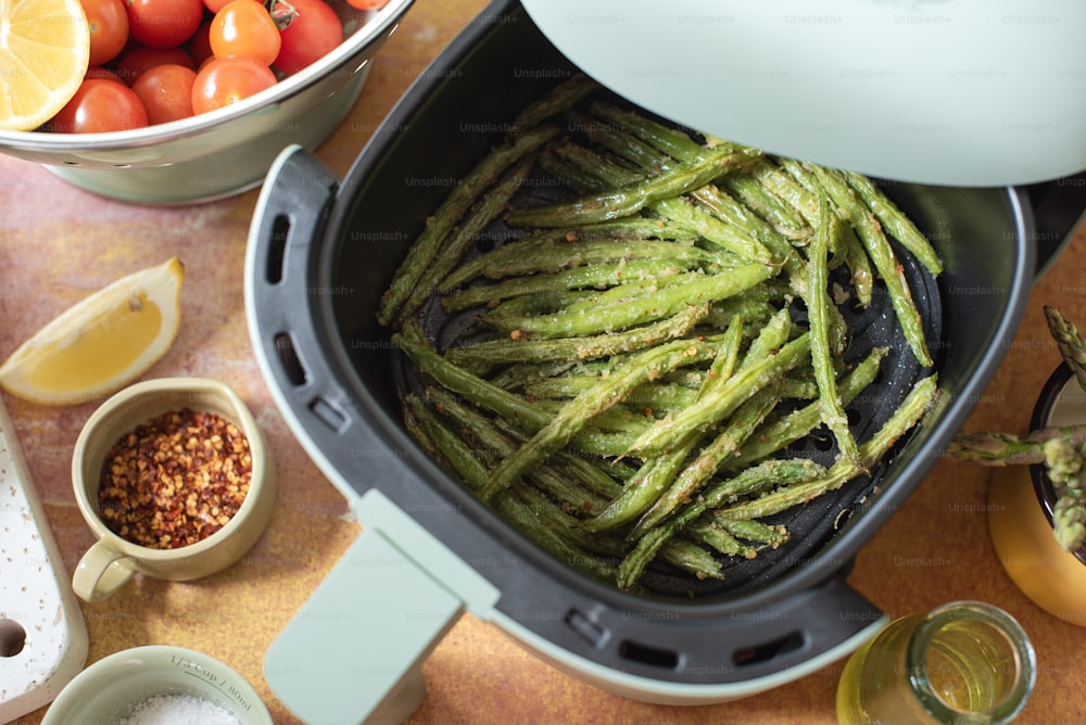 a pan filled with green beans next to a bowl of tomatoes