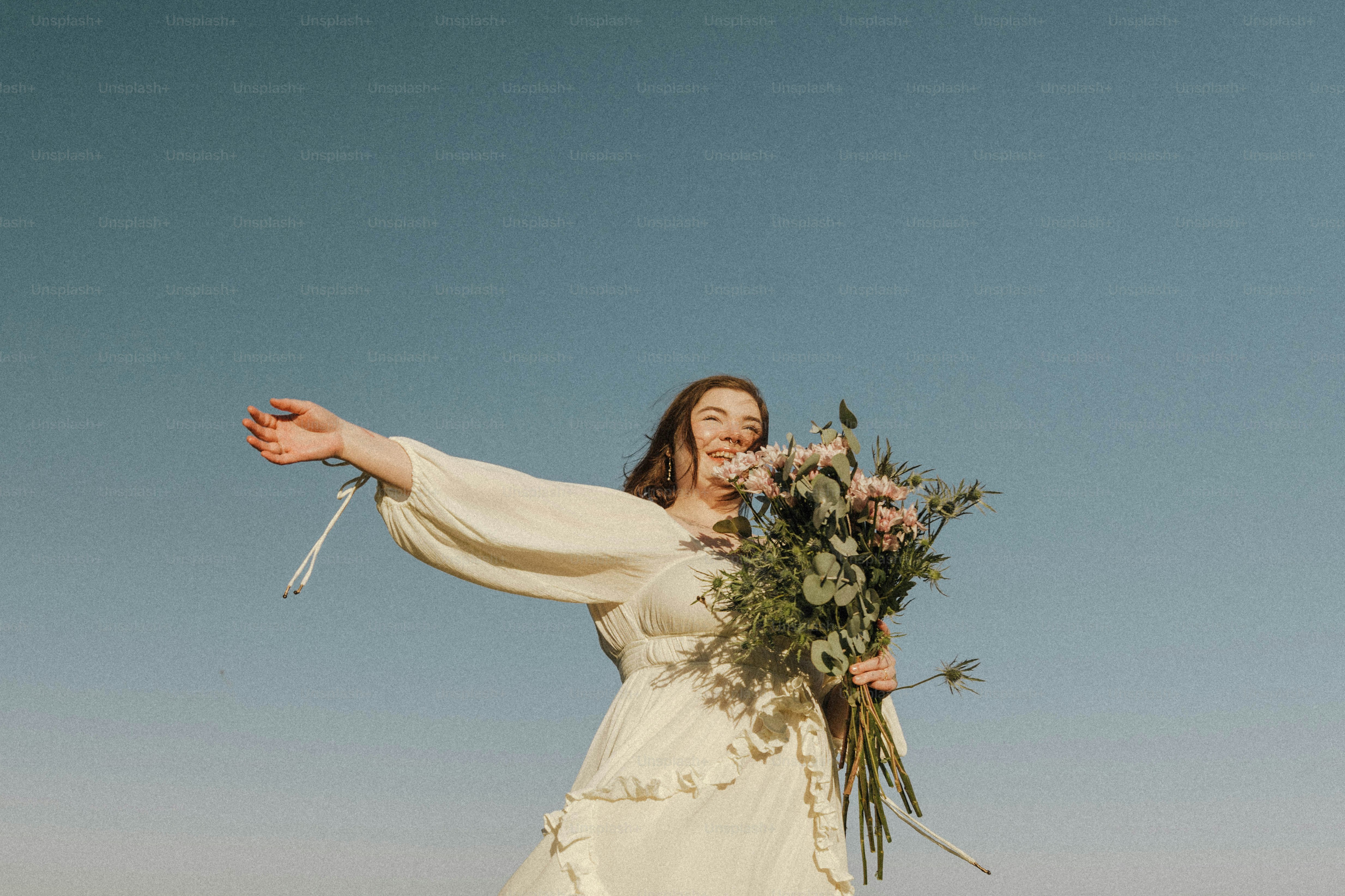 a woman in a white dress holding a bouquet of flowers