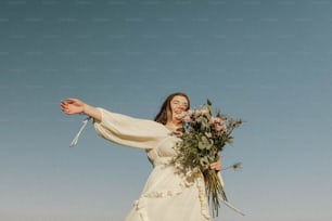 une femme en robe blanche tenant un bouquet de fleurs