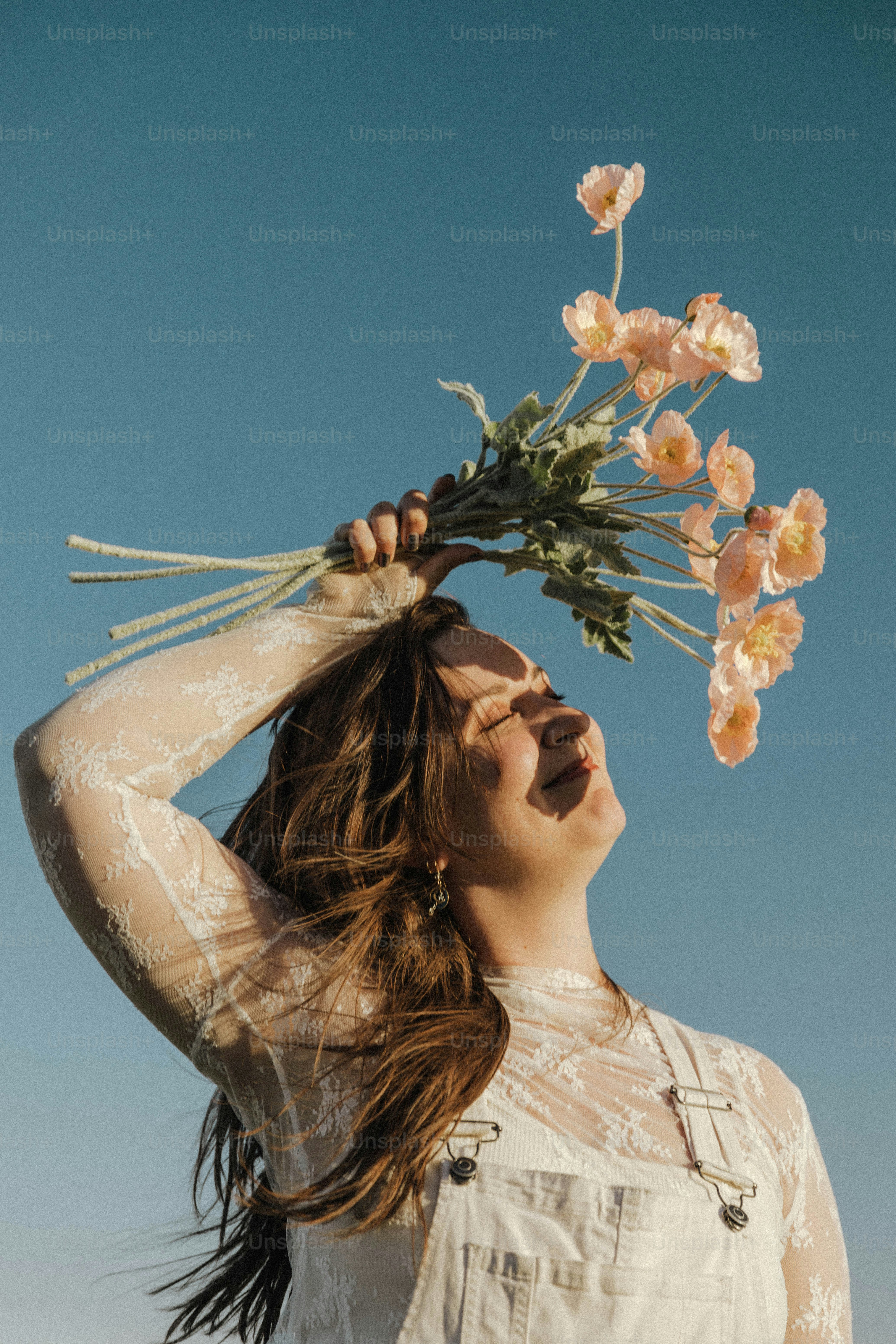 a woman holding a bunch of flowers on her head