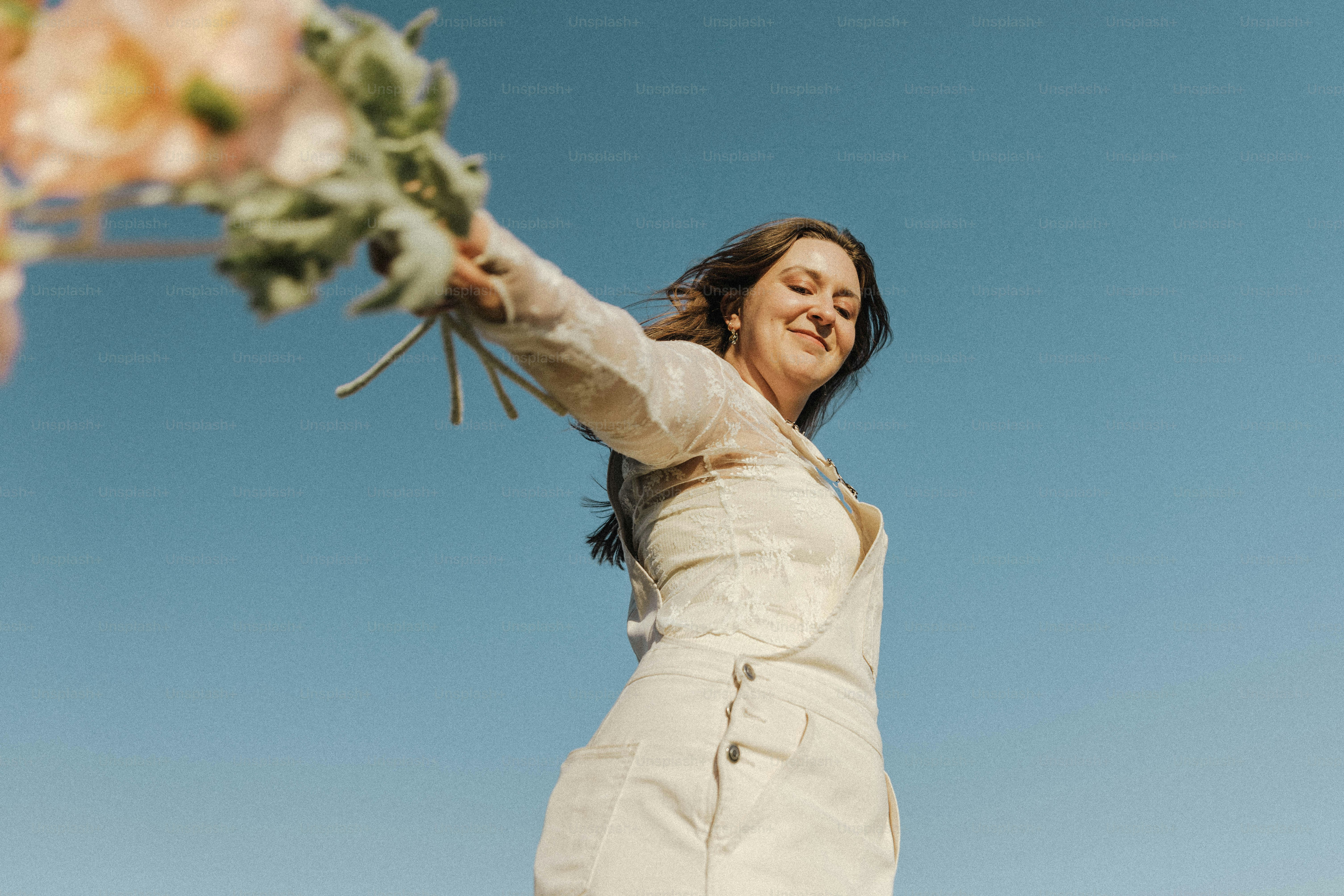 a woman in a white dress holding a bouquet of flowers