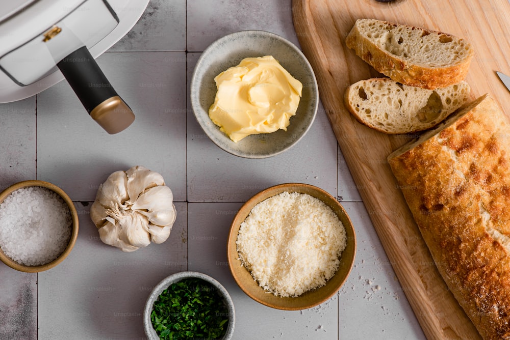 pan, mantequilla, ajo y otros ingredientes en una tabla de cortar