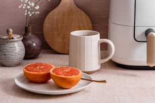 two halves of an orange on a plate next to a coffee maker