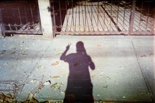 l'ombra di una persona in piedi su un marciapiede