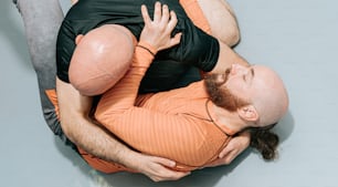 a man in an orange shirt is wrestling with another man