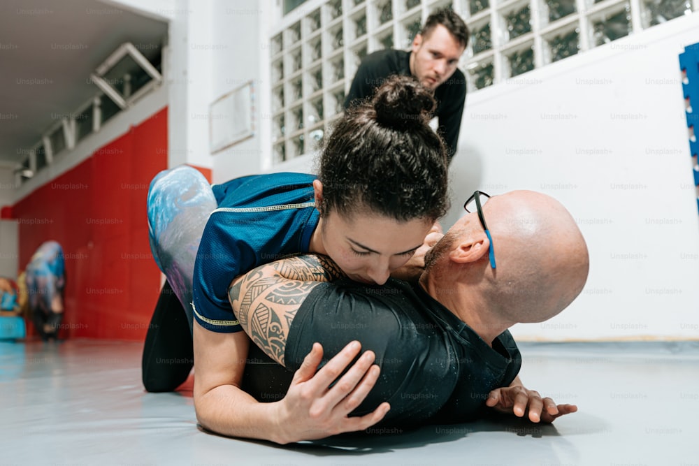 a man in a blue shirt is wrestling with another man in a black shirt