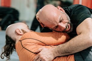 Un hombre con la cabeza calva sosteniendo a otro hombre