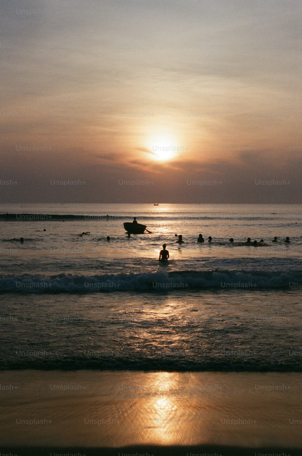 a group of people in the ocean at sunset